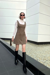 a lady wears a brown vest dress with a white top